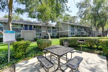 BBQ Area with Picnic Table, Area Rules Sign, Bushes, and Trees at Pinecrest Apartments, Davis, California